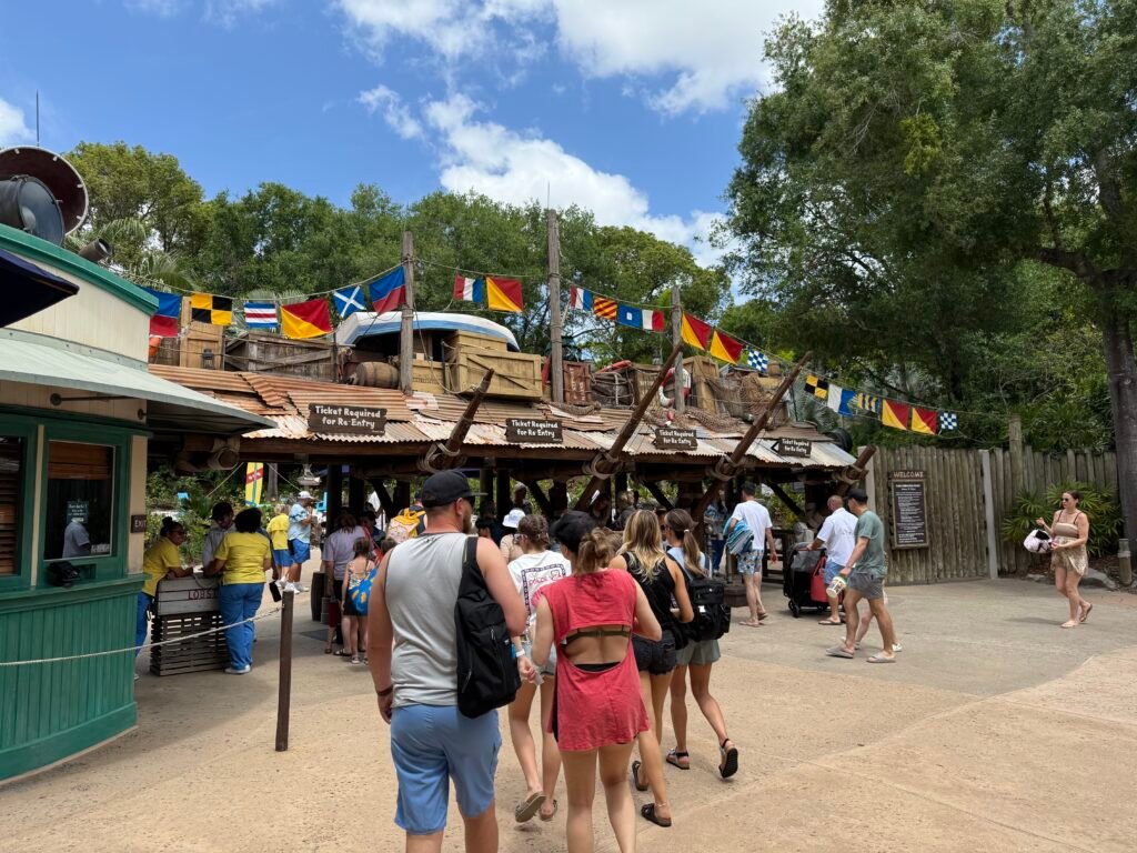 Guests lined up at the entrance of Typhoon Lagoon Water Park, surrounded by colorful flags and a sunny atmosphere.
